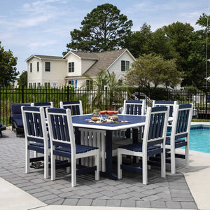 Candles, greenery and orange mimosas arranged on a navy poly patio dining table between white slat chairs