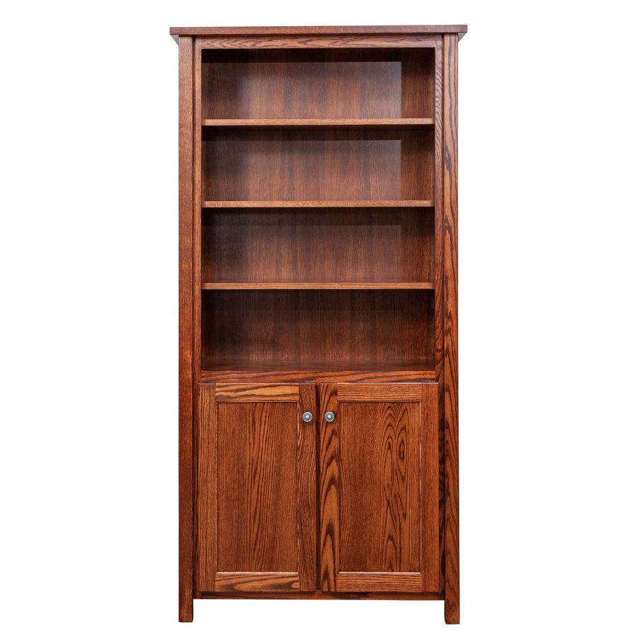 Six foot oak bookcase with four open adjustable shelves above two paneled doors with round knobs