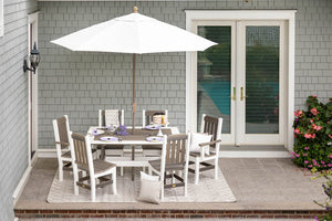 Six mission slat back poly chairs around a white and weatherwood dining table with a white market umbrella