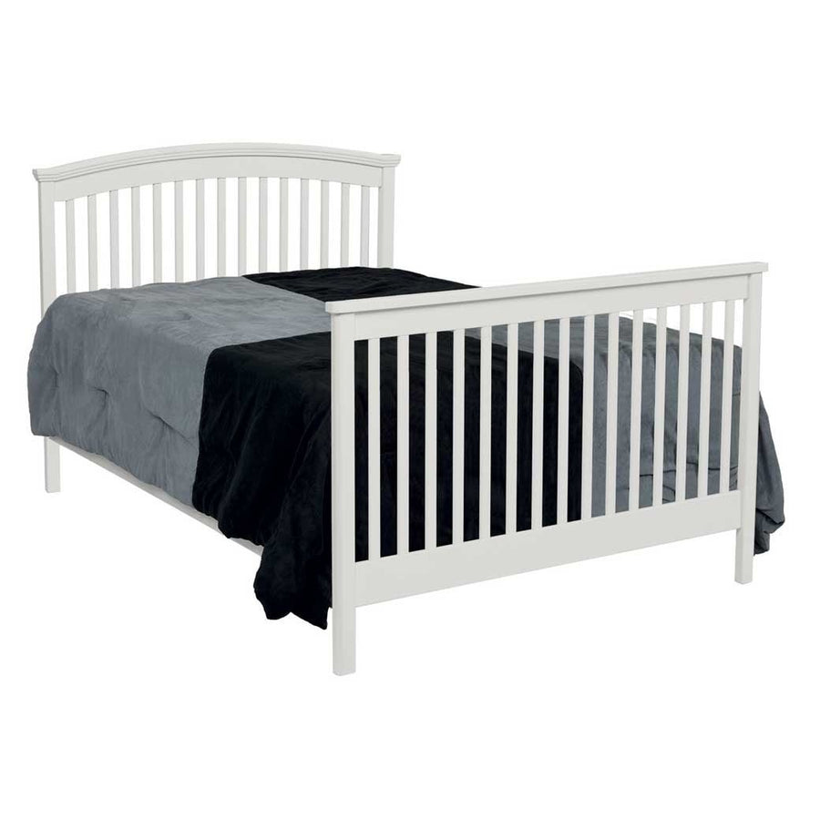 White convertible crib converted to a full bed with arched slat headboard, slatted footboard and gray bedding
