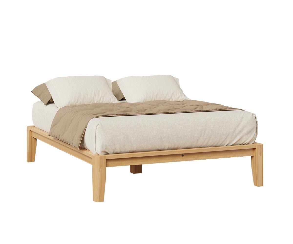 Headboard free natural wood platform bed with low side rails, tapered legs and neutral linen bedding on a white background