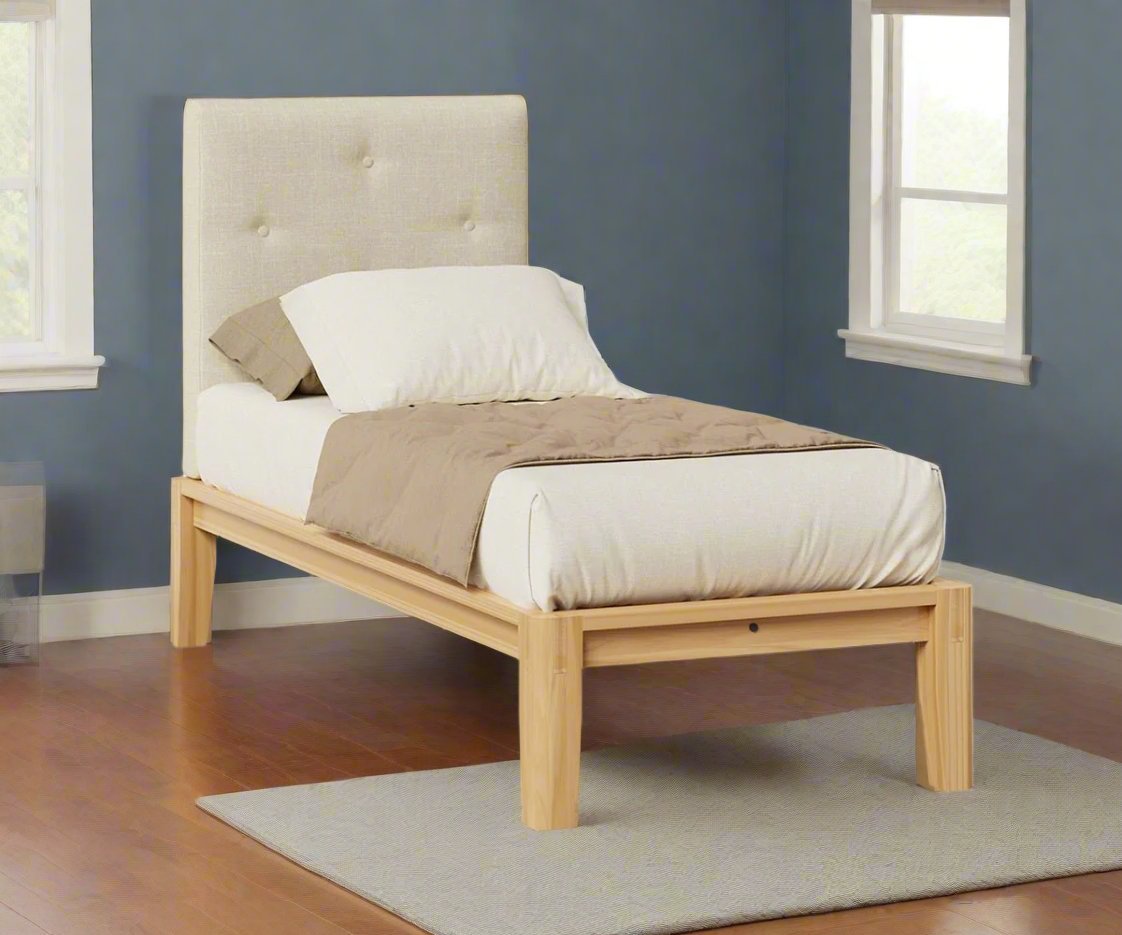 Twin platform bed with a cream button tufted upholstered headboard and natural wood frame in a blue painted bedroom