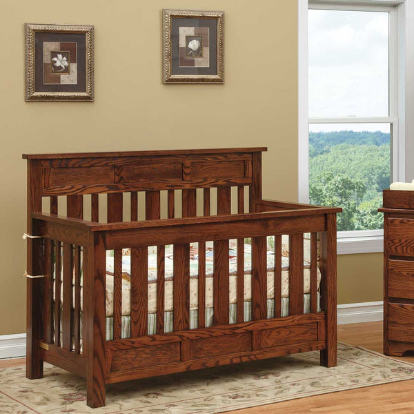Oak Hudson convertible crib with raised panel headboard, slat sides and lower panel rail in a warm nursery