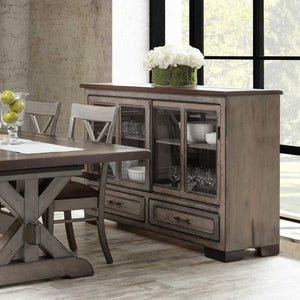 Weathered gray sliding glass door server with dishes and glassware inside, two drawers and hydrangeas on the plank top