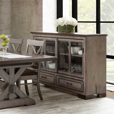 Weathered gray sliding glass door server with dishes and glassware inside, two drawers and hydrangeas on the plank top