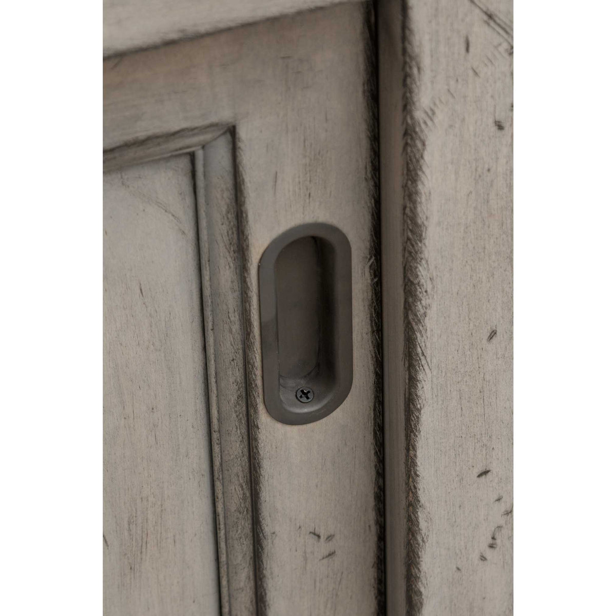 Recessed oval pull on the gray server's sliding door, showing the distressed painted finish and molded panel