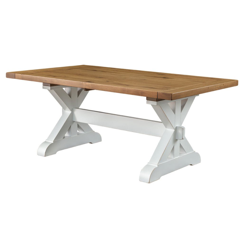 Trestle dining table with a warm oak plank top and crisp white X base with center stretcher on a white background