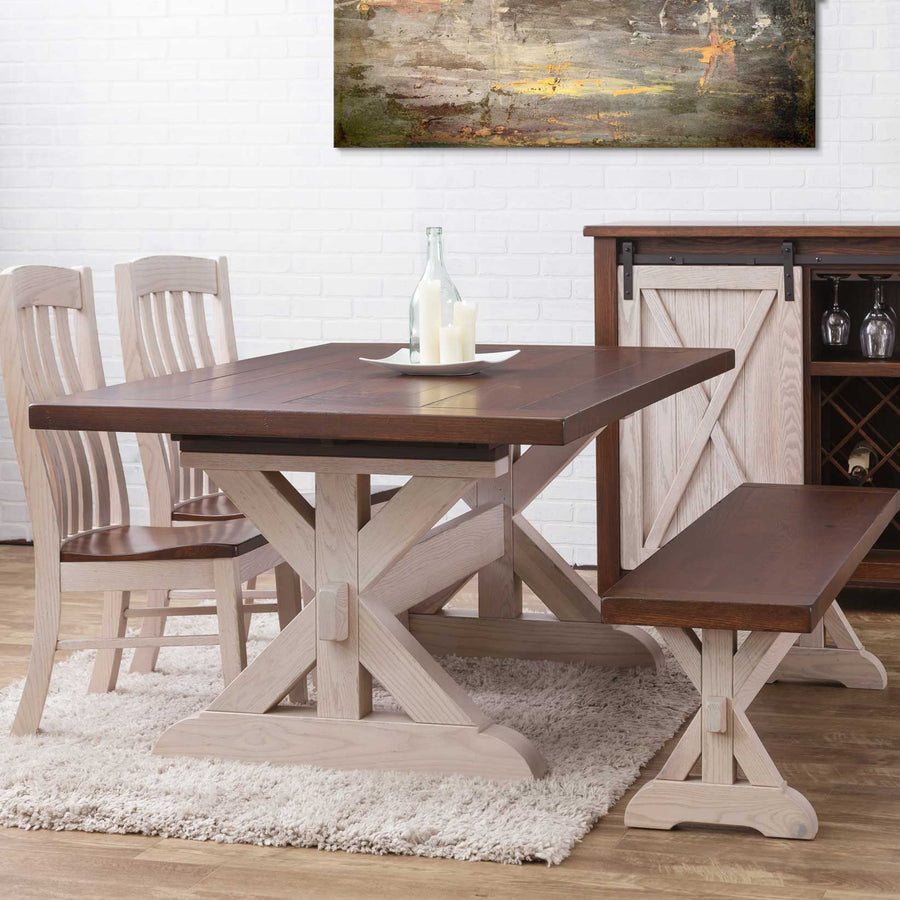 Two-tone X base trestle table with dark plank top and white washed base, slat back chairs, bench and barn door wine cabinet