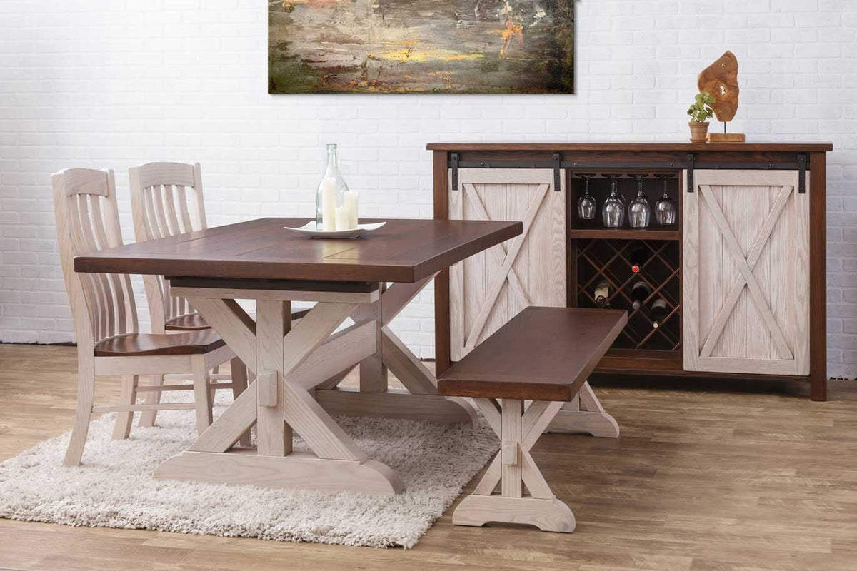 Two-tone X trestle table and bench with white washed bases and walnut tops beside a barn door wine cabinet