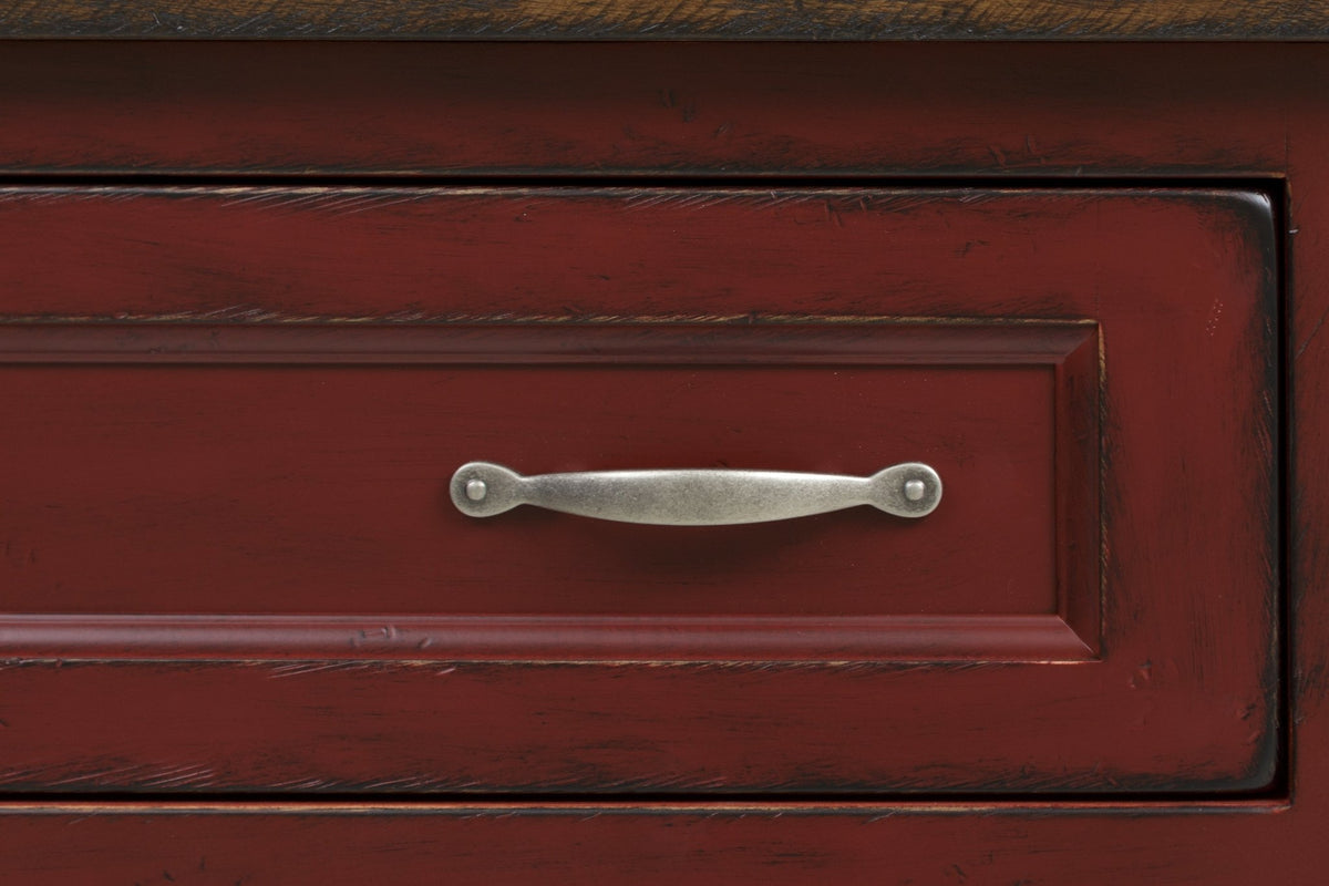 Detail of a distressed red drawer front with a molded frame and an antique pewter bail pull