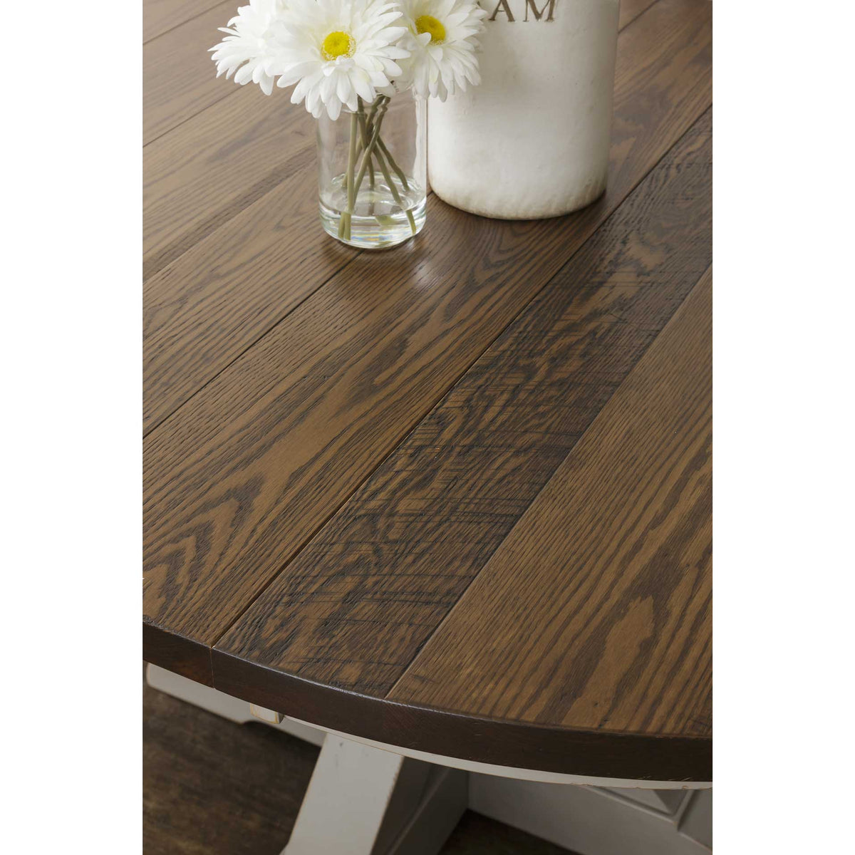 Close-up of the round table top showing oak plank seams, cathedral grain and the painted beveled edge