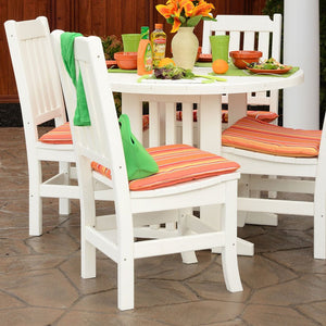 White poly dining chairs with orange striped cushions around a round white patio table on stone paving