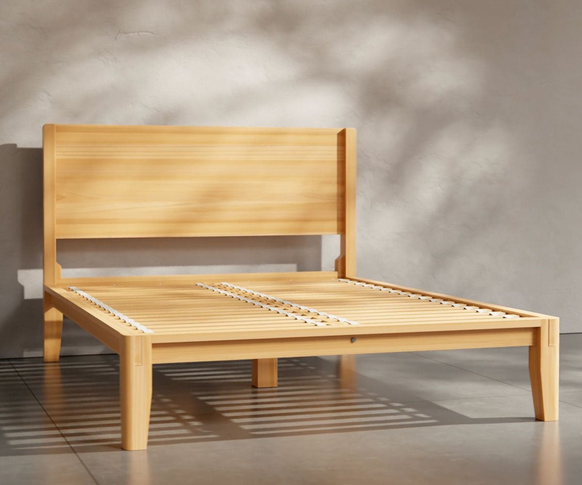 King size natural pine platform bed with a plank panel headboard and white bedding in a sunlit plaster walled room
