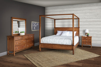 Cherry canopy bedroom set with a tall poster canopy queen bed, seven-drawer dresser, mirror and nightstand on a jute rug