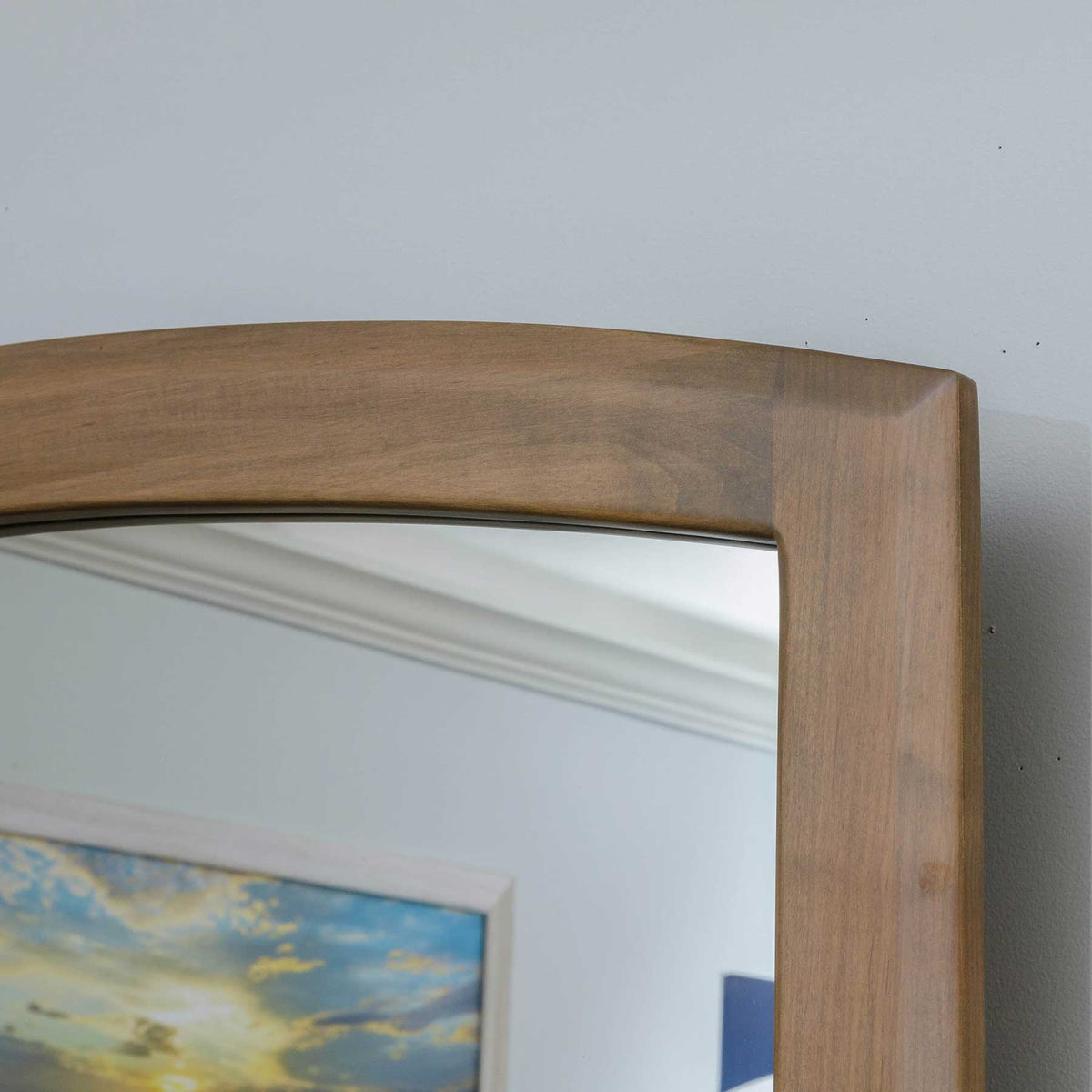 Corner detail of the arched dresser mirror frame showing gently curved wood and a rounded profile