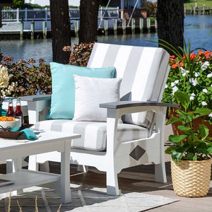 White poly patio club chair with gray and white striped cushions and diamond side accent on a waterfront deck