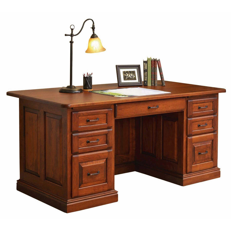 Executive panel desk in cherry with six drawers, center drawer, dark bronze pulls and a desk lamp on top