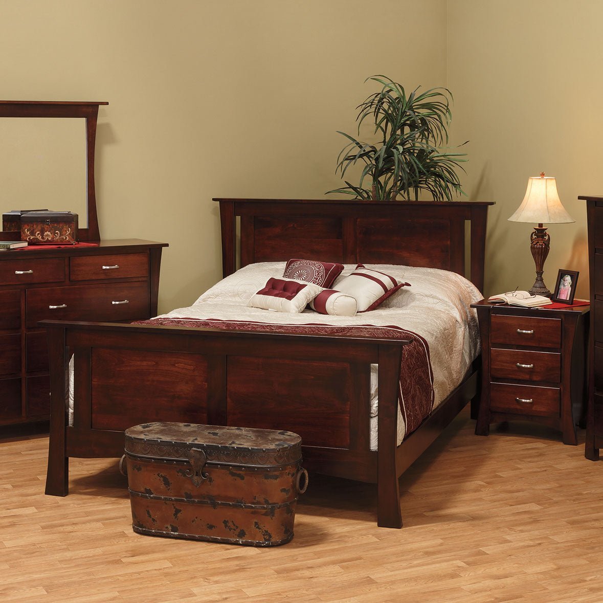 Dark cherry panel bed with matching dresser, mirror and nightstand in a warm toned bedroom