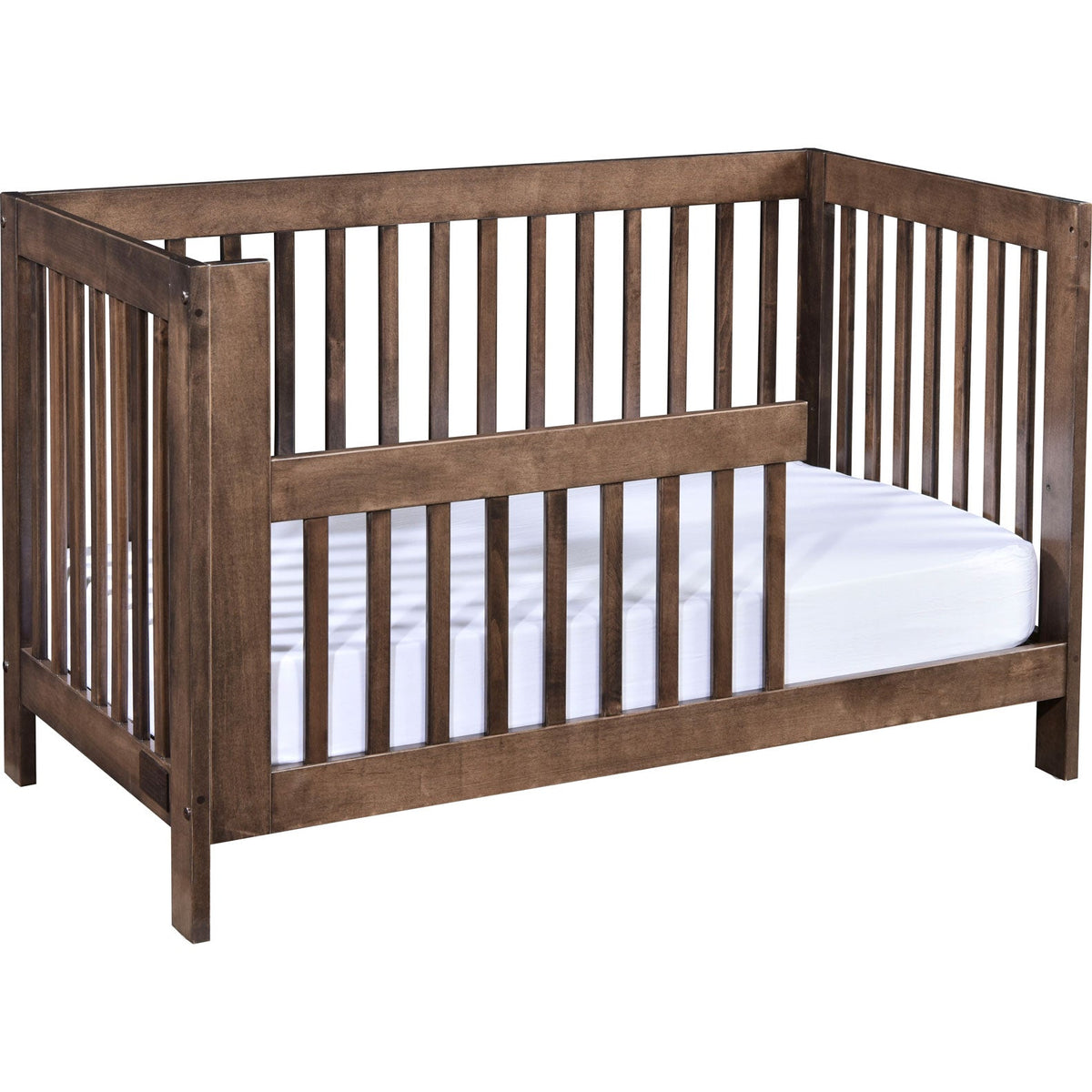 Weathered brown crib set up as a toddler bed with a partial guard rail and open entry side