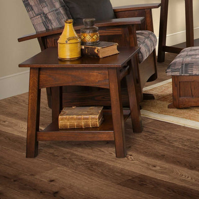 Dark brown Santa Fe end table with drawer and lower shelf holding pottery and antique books on wood flooring