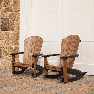 Pair of brown and black kid's Adirondack rocking chairs on pavers against a white and stone wall