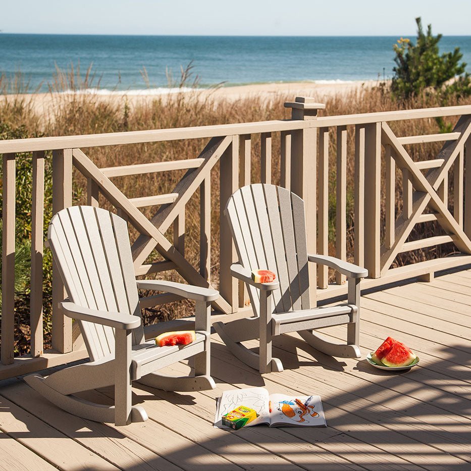 Small poly Adirondack rocking chairs on a beachfront deck with a coloring book and plate of watermelon