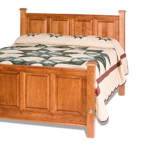 Cherry raised panel headboard with four recessed panels and square posts above a quilted bed