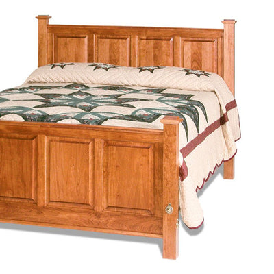 Cherry raised panel headboard with four recessed panels and square posts above a quilted bed