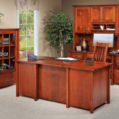 Cherry executive desk with paneled back styled in an office with a matching credenza hutch, bookcase, plant and monitor