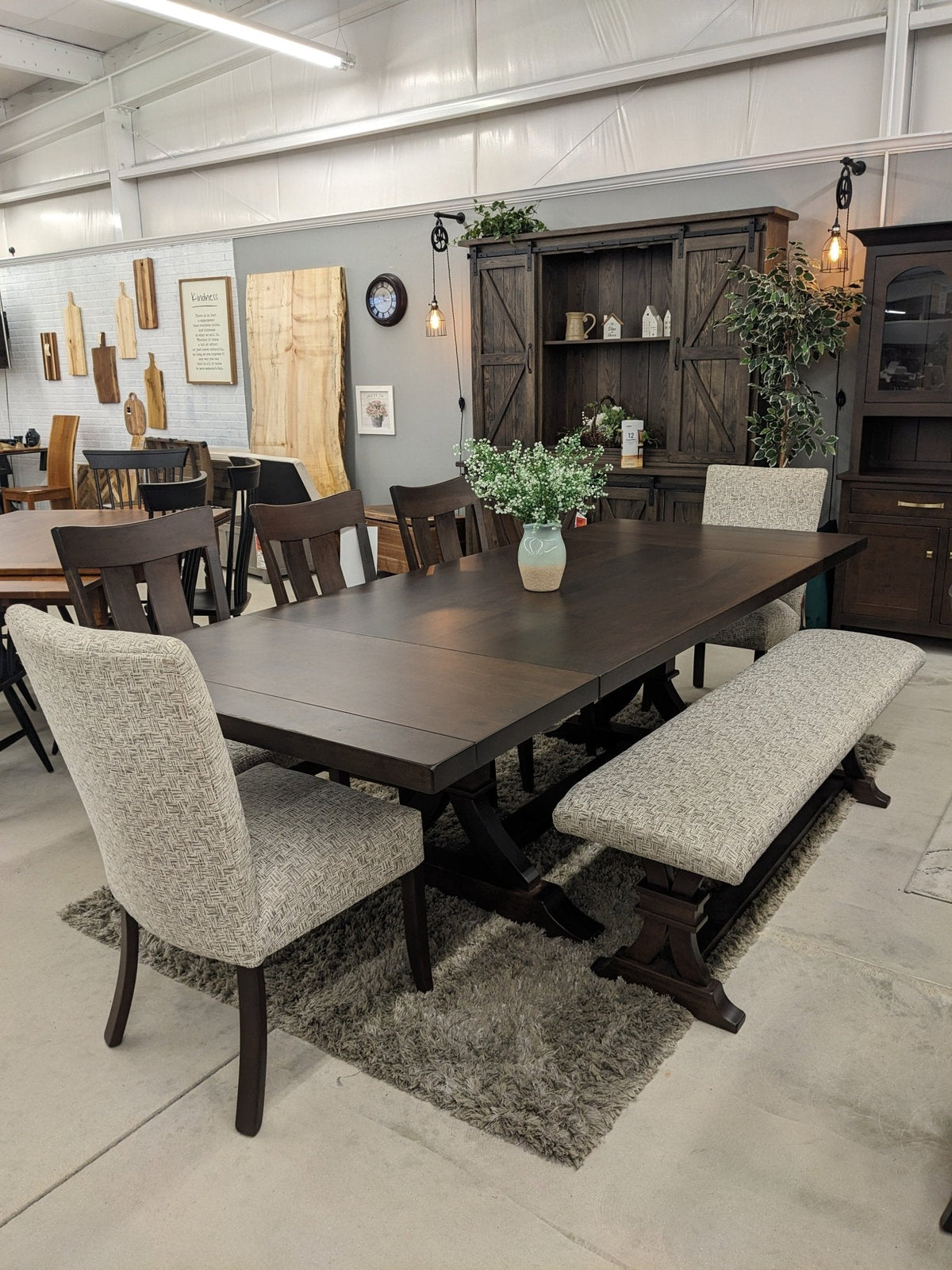 Extended Sherwood trestle table in the showroom with two leaves in place, tweed upholstered chairs and bench