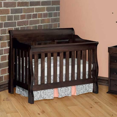 Espresso stained sleigh crib with slatted sides and panel headboard in a nursery with pink walls