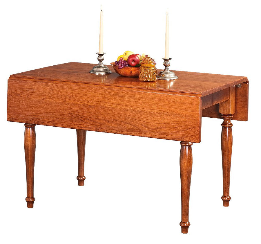 Cherry drop leaf table with one leaf lowered, fluted turned legs, candlesticks and a bowl of fruit on the top