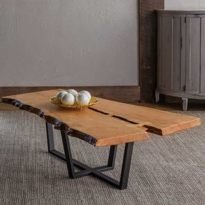 Live edge natural wood coffee table with a split plank top and a black steel X-shaped base on a woven rug