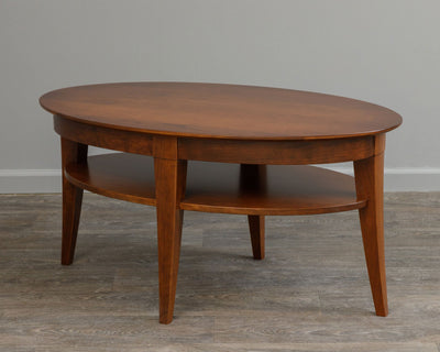Oval coffee table in a cherry finish with a beveled top, splayed tapered legs and an oval lower shelf