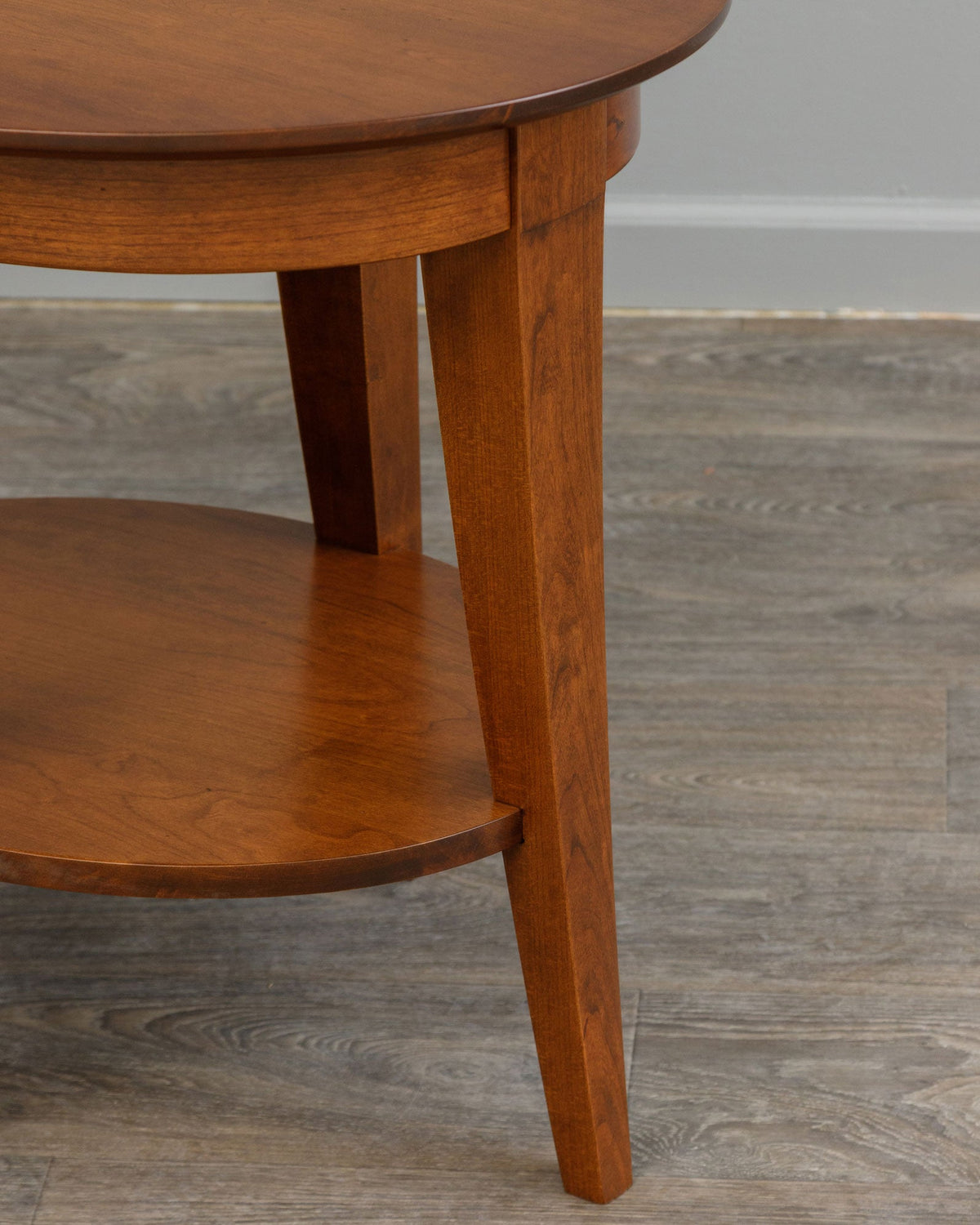 Leg and shelf detail of the oval end table showing the tapered leg profile and curved lower shelf