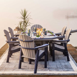 Driftwood and navy poly fire pit dining table with six Adirondack dining chairs on a rug over a misty dock