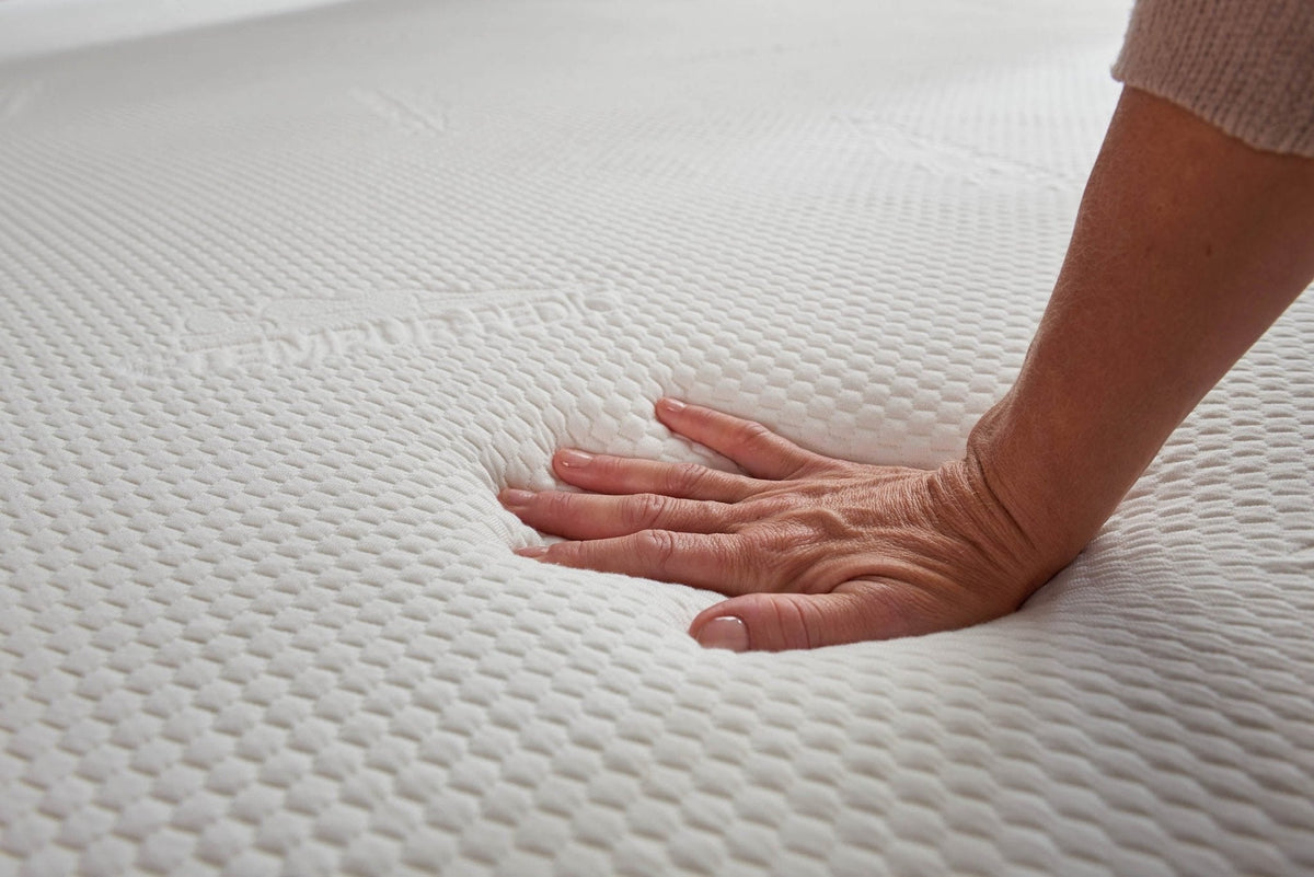 Hand pressing into the memory foam topper surface to show the pressure relieving indentation in the knit cover