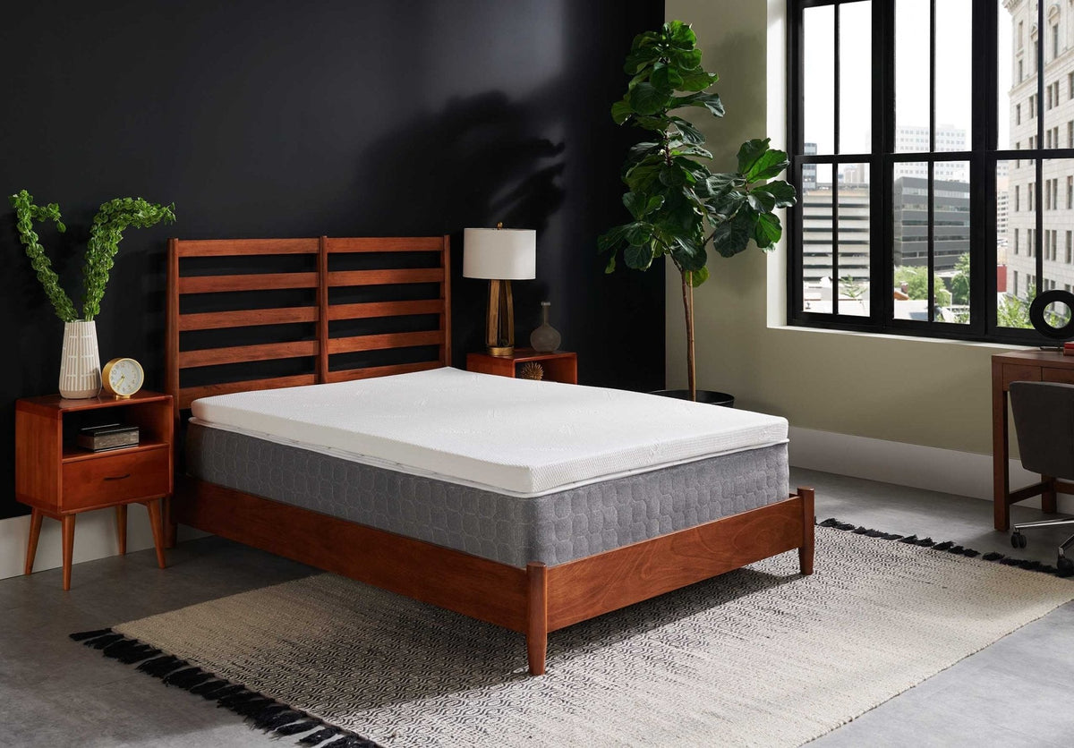 Bedroom scene with the memory foam topper on a gray mattress in a walnut platform bed by a large city window