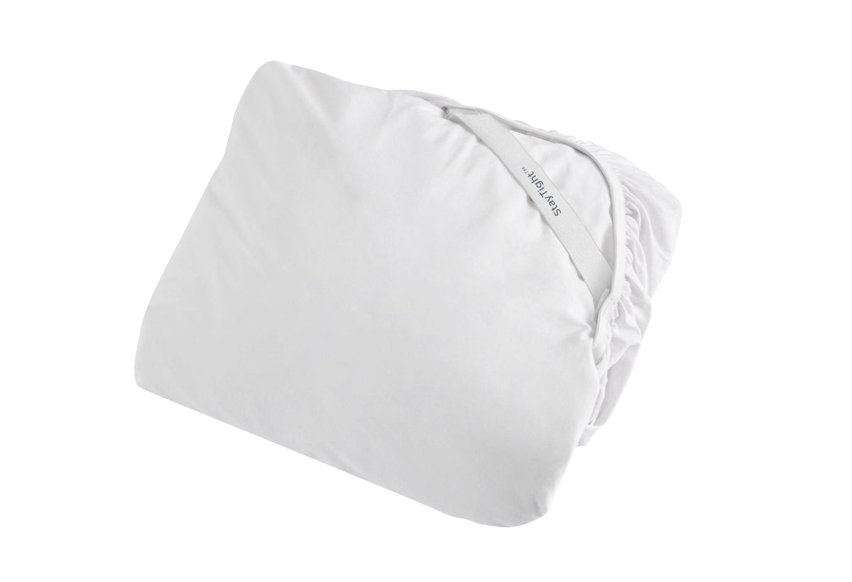 White fitted mattress protector folded to show its stretch skirt and elastic edge, on a white background