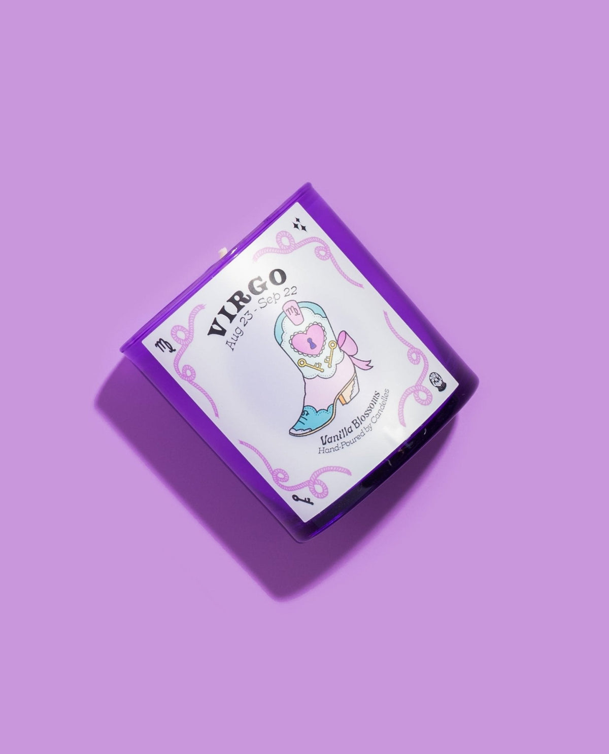 Virgo vanilla blossoms zodiac candle tilted on lilac showing the pastel heart detailed cowboy boot label