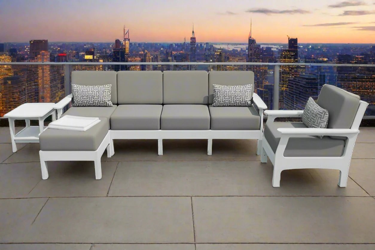 White poly patio sofa set with gray cushions, matching chair, ottoman with tray and side table on a city rooftop