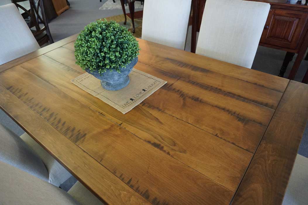 Top down view of the Westin table's distressed maple planks with a runner and topiary in a stone urn