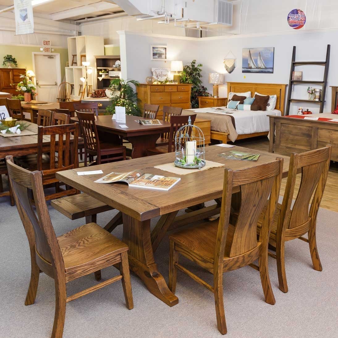 Oak Westin trestle table displayed in the showroom with four slat back side chairs and a candle centerpiece
