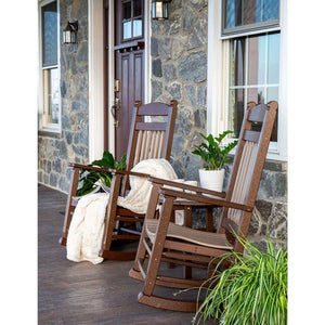 Brown and tan poly rockers with a cream throw and potted plants on a stone farmhouse front porch
