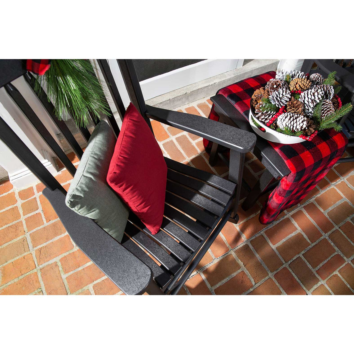 Overhead view of a black poly rocking chair with red and sage pillows and a buffalo check throw at Christmas
